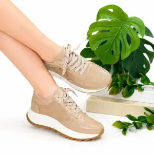 Zapato de cuero beige con textura snake print y suela track blanca y marrón, mostrados de perfil con plantas verdes de fondo.